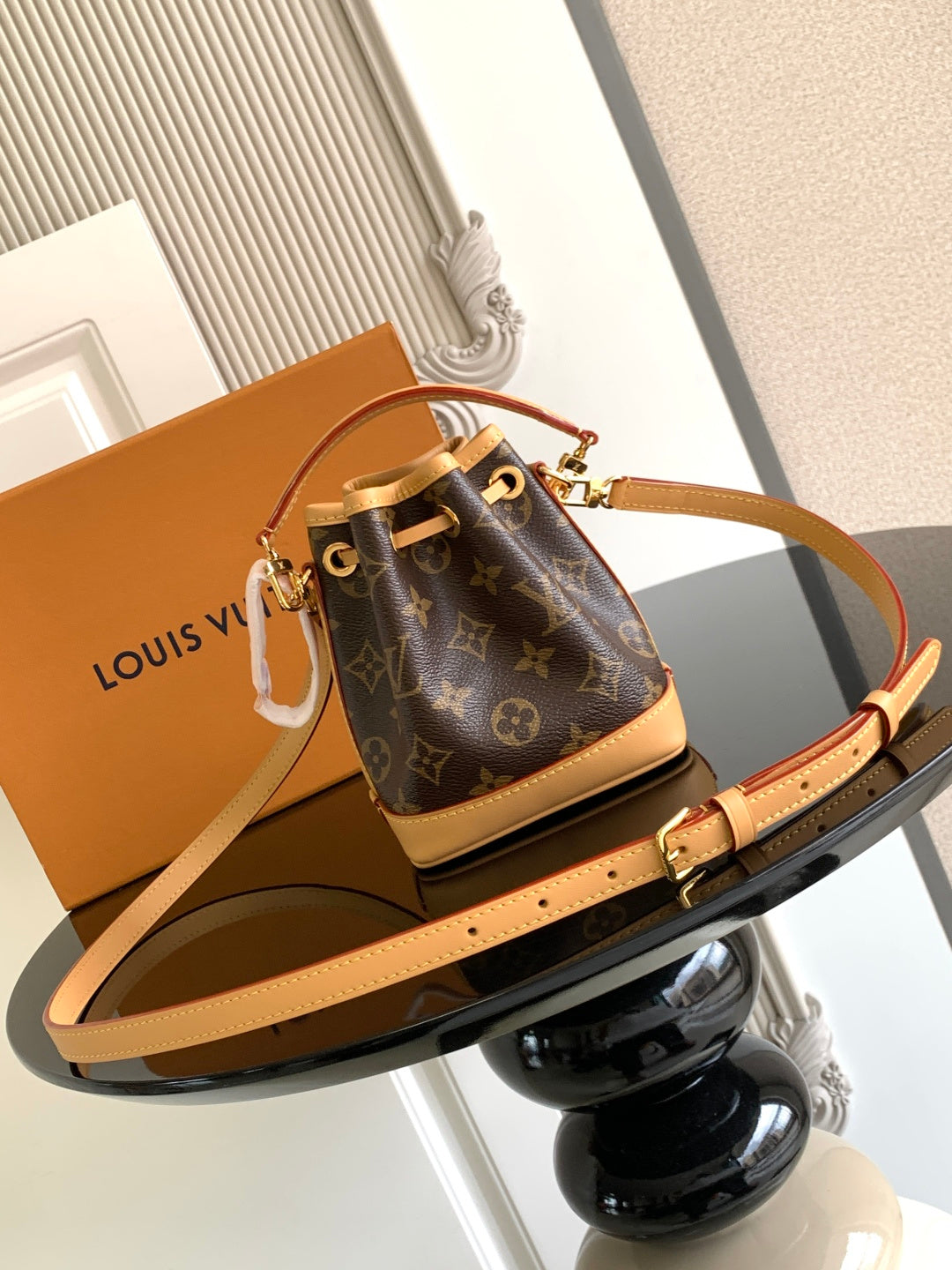 Louis Vuitton monogram bucket bag with tan crossbody strap and gold-tone clasp