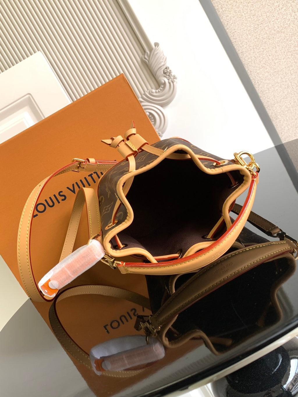 Louis Vuitton monogram bucket bag with tan trim, open interior, and drawstring
