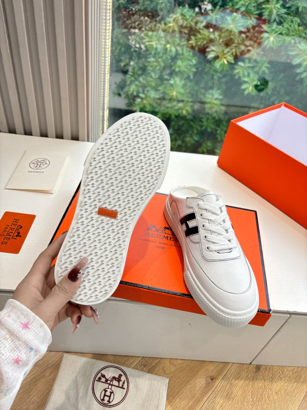 White leather sneaker soles with speckled tread and black H logo upper