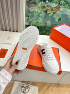 White leather sneaker soles with speckled tread and black H logo upper