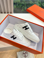 White leather sneakers with black H logo detail and flat woven-texture sole
