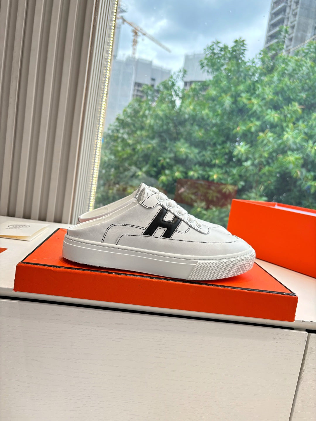 White leather sneaker with black H side logo, lace-up upper and low rubber sole