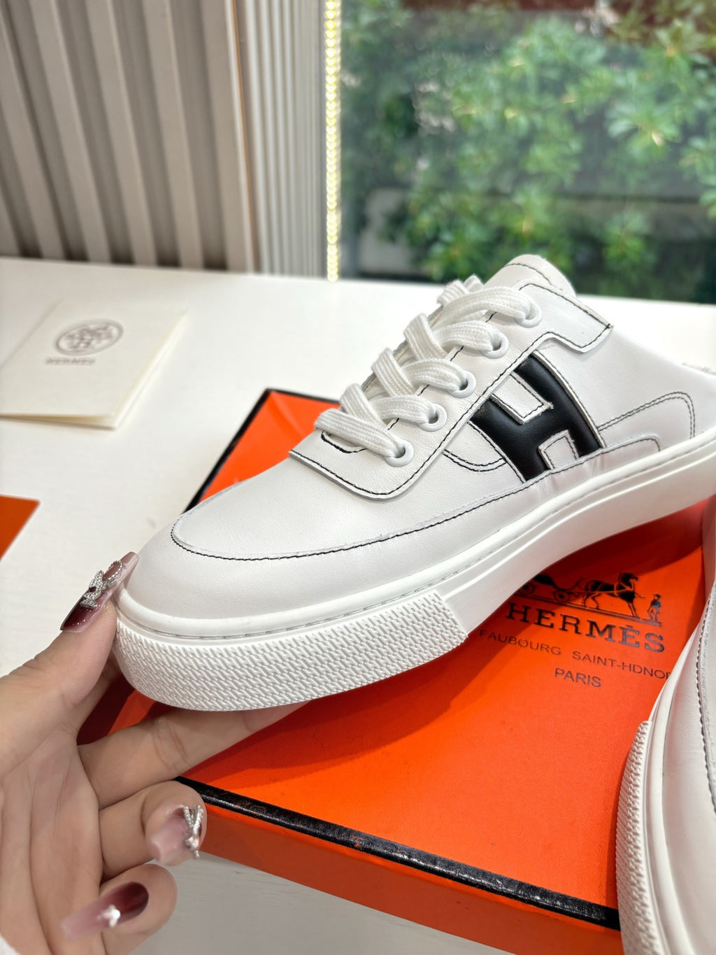 White leather sneaker with black H logo, lace-up front and thick textured sole