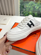 White leather sneaker with black H logo, lace-up front and thick textured sole