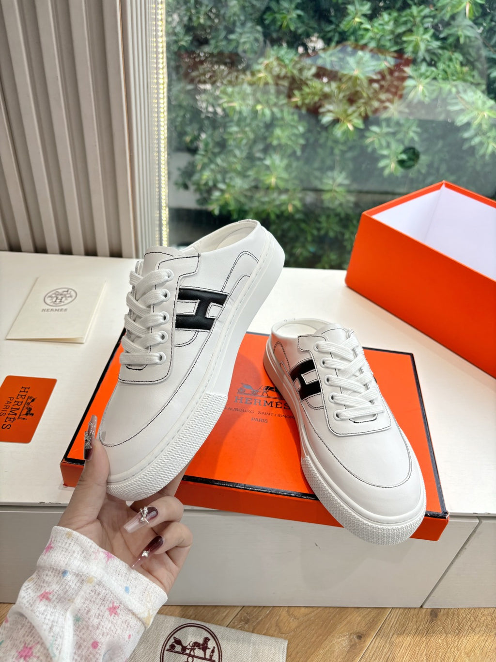 White leather sneakers with black H logo, lace-up front and textured rubber sole
