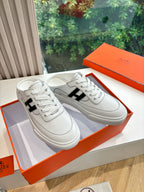 White leather sneakers with black H logo and white laces, low-profile sole