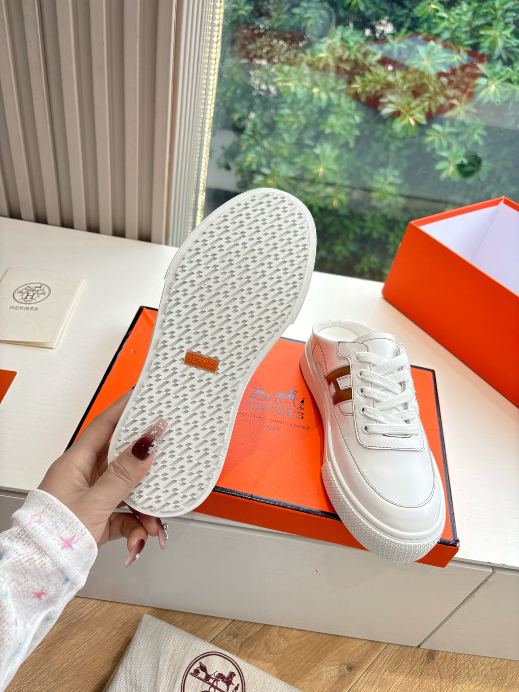 White Hermes sneaker outsole with textured tread, brown H logo on heel