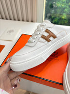White Hermes sneaker with brown H logo on side, laced upper close-up