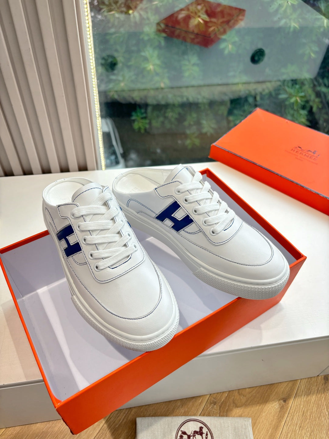 White leather low-top sneakers with blue H logo and white laces