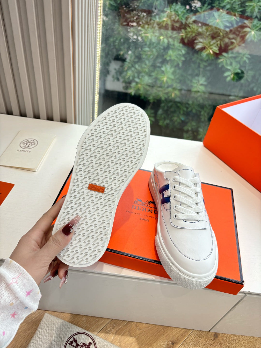 White low-top sneakers showing textured outsole, blue H side logo