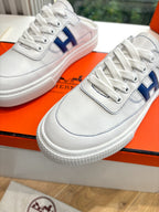 Close-up of white lace-up sneakers with blue H logo on the side