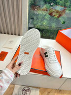 White sneakers showing textured tread sole, held above orange shoebox