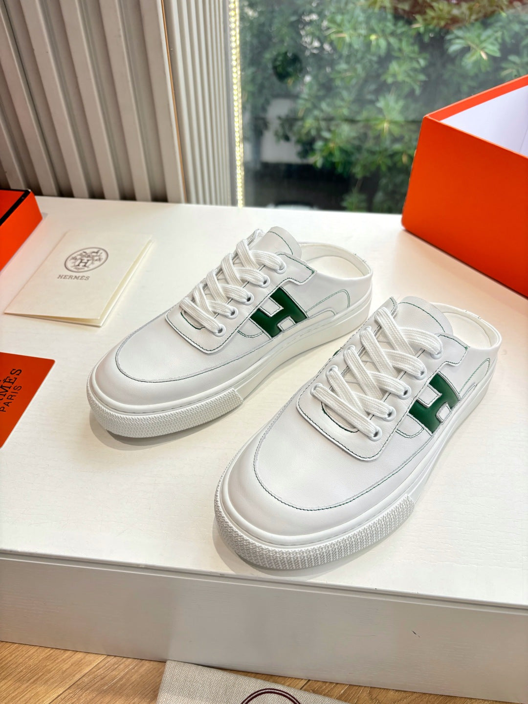 White leather sneakers with green H logo and lace-up front, in box