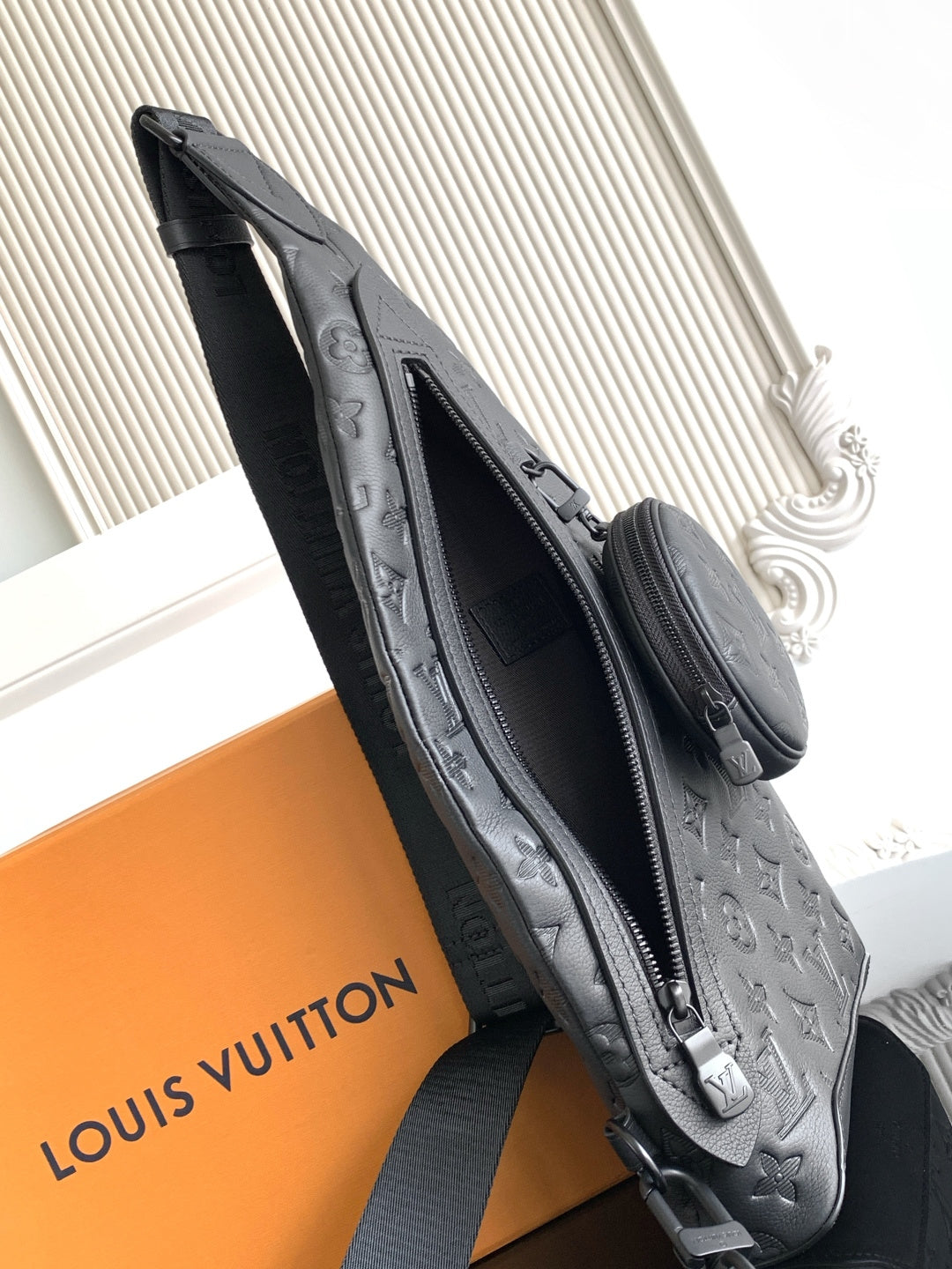 Louis Vuitton bag side view with zipper opening, dark embossed monogram, crossbody strap