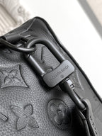 Louis Vuitton bag close-up of strap hardware with leather pull tab and embossed pattern