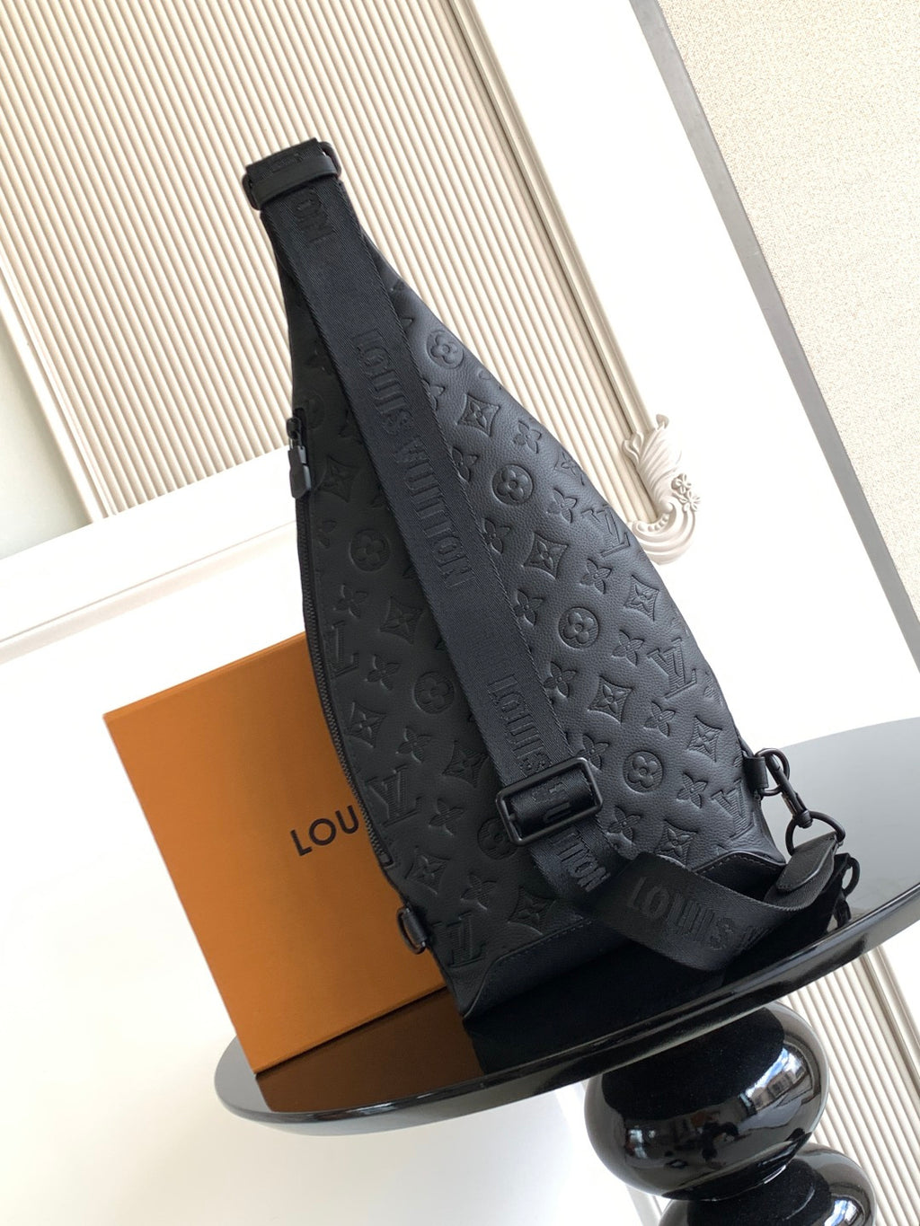 Louis Vuitton bag angled view with top handle and dark embossed monogram pattern