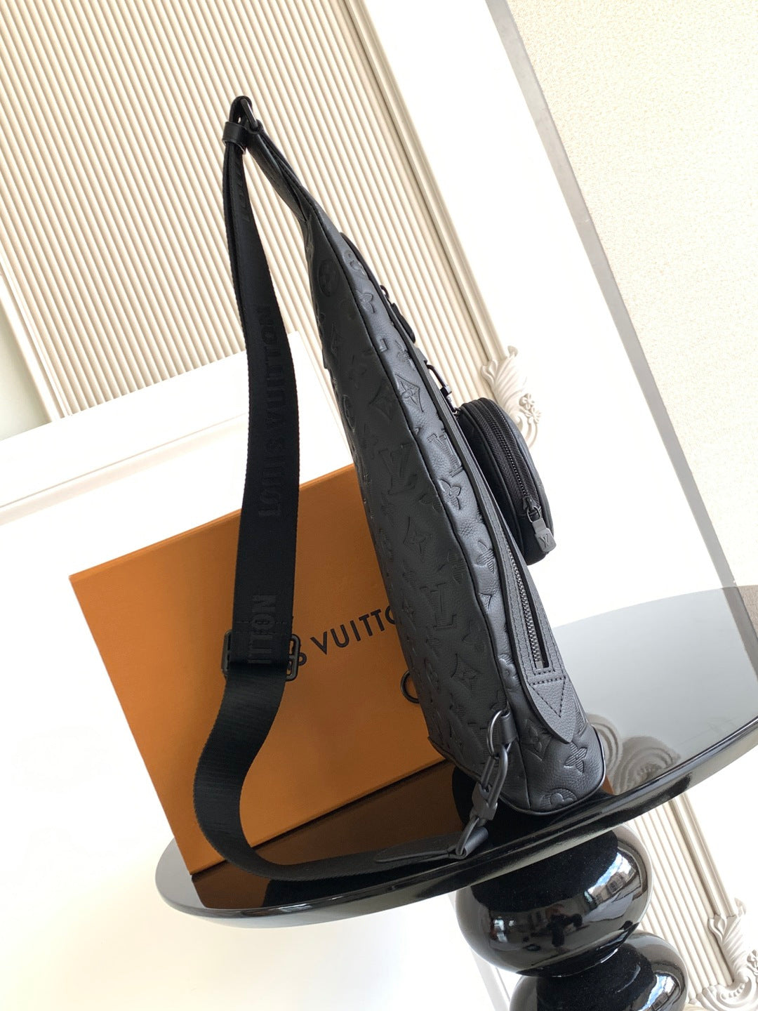 Louis Vuitton bag side view with long strap and zipper pocket in dark embossed leather