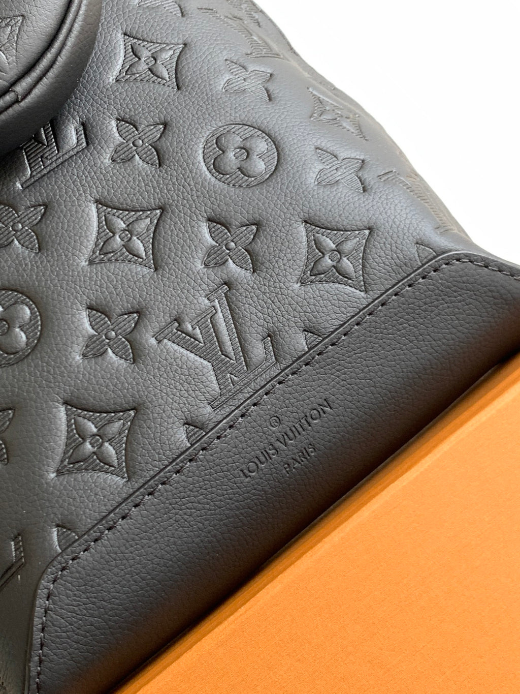 Louis Vuitton bag close-up of dark embossed leather and logo-stamped leather panel