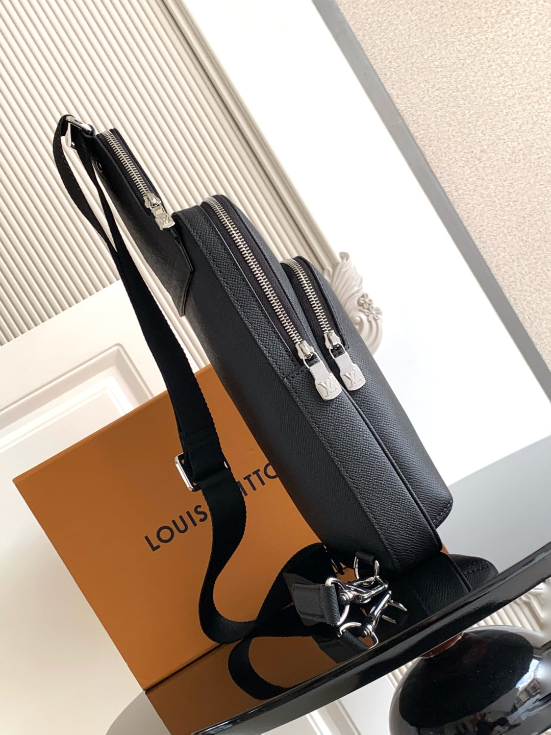 Louis Vuitton black leather crossbody bag, side view with zip pockets