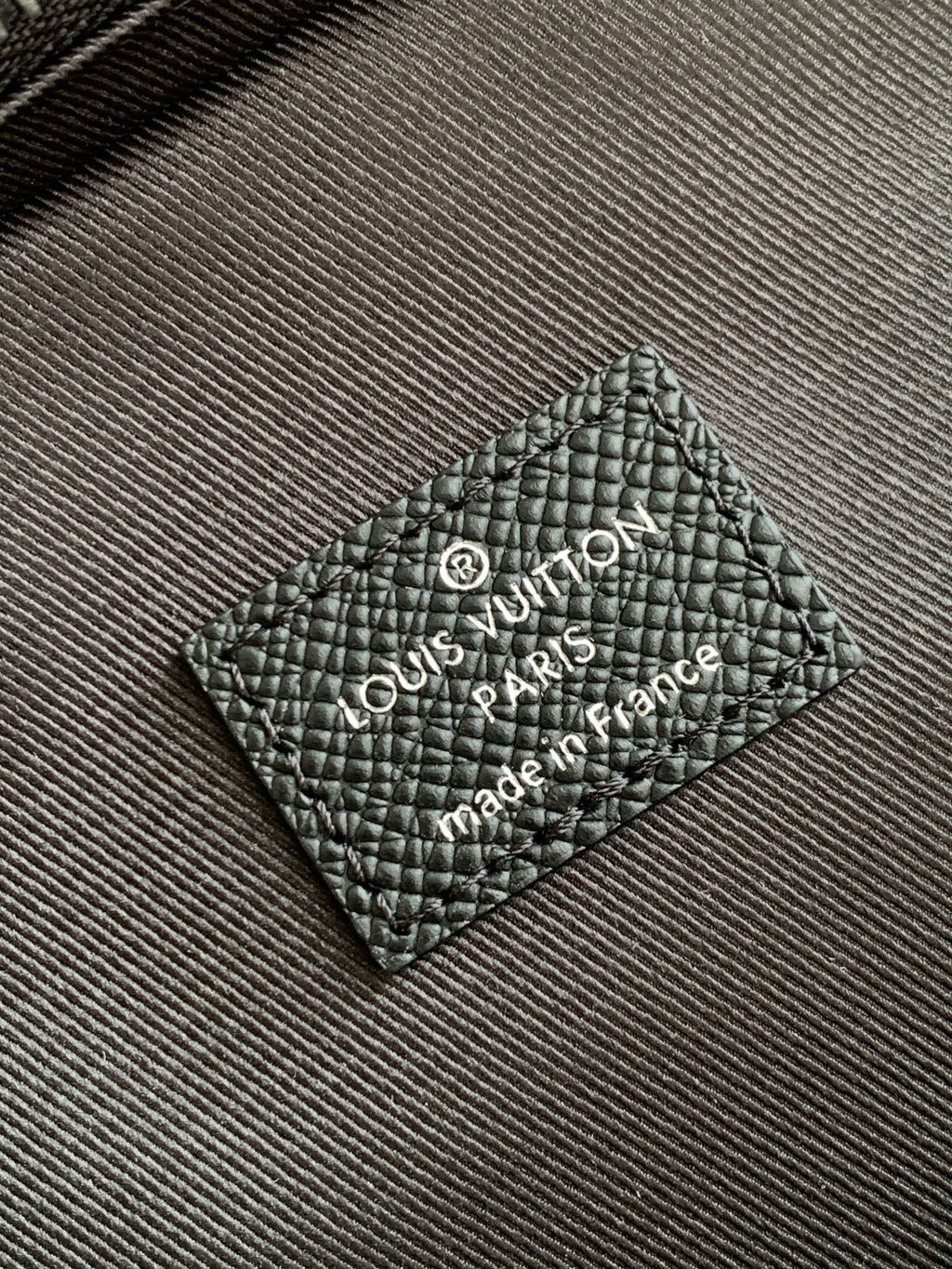 Louis Vuitton black leather logo patch with "Louis Vuitton" text
