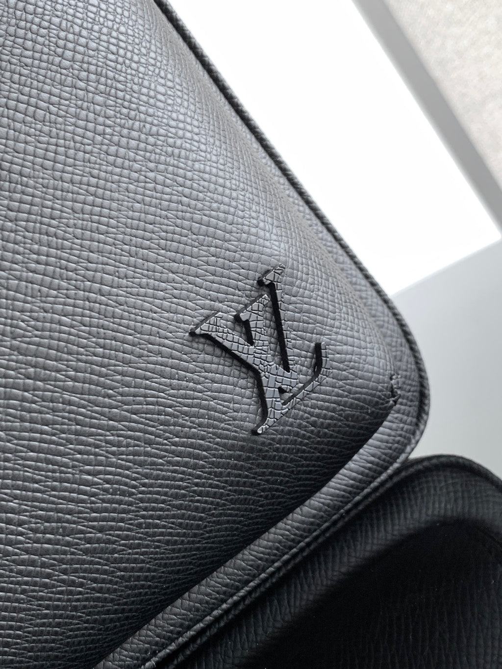 Louis Vuitton black leather corner with embossed logo and stitched edge