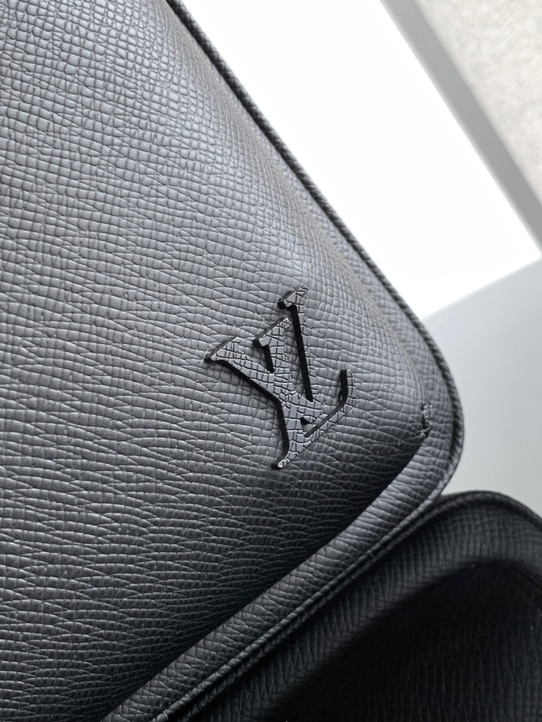 Louis Vuitton black leather corner with embossed logo and stitched edge
