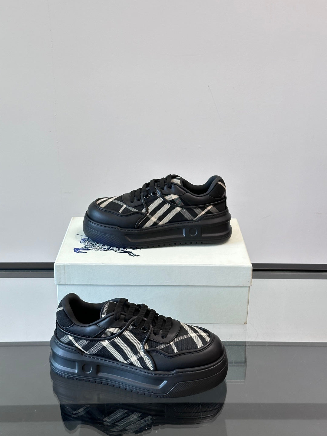 Black lace-up sneakers with plaid stripe detail and textured sole edge, side view