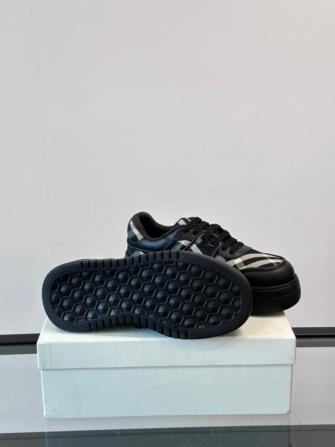 Black sneakers with honeycomb-textured outsole and plaid side panel, side view