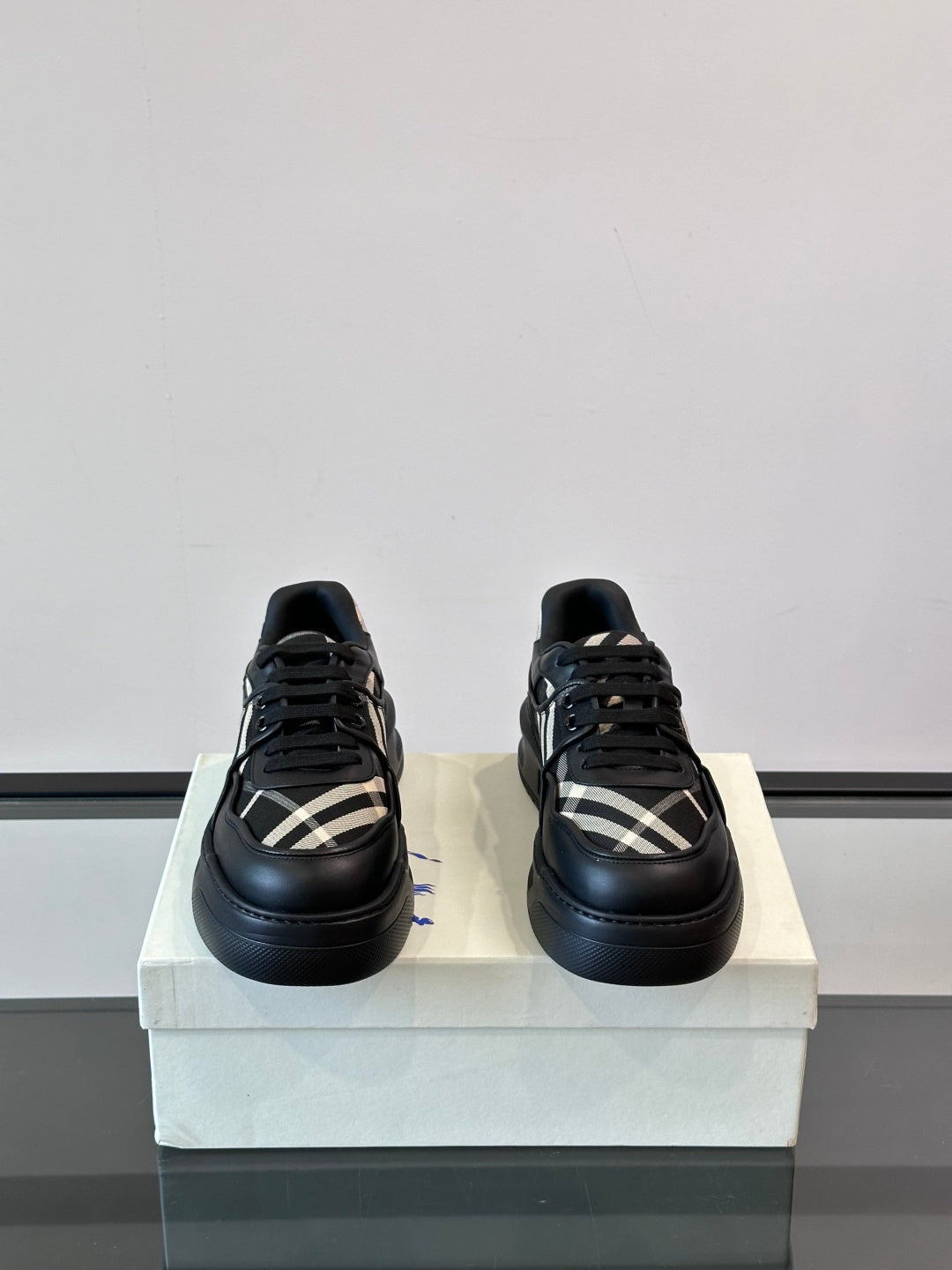 Black lace-up sneakers with plaid side stripe pattern and chunky low profile sole