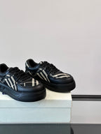 Black low-top sneakers with plaid stripe panels and thick sole, angled view