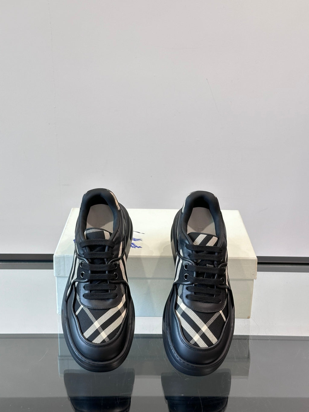 Black lace-up sneakers with plaid quarter panels and low chunky outsole, front view