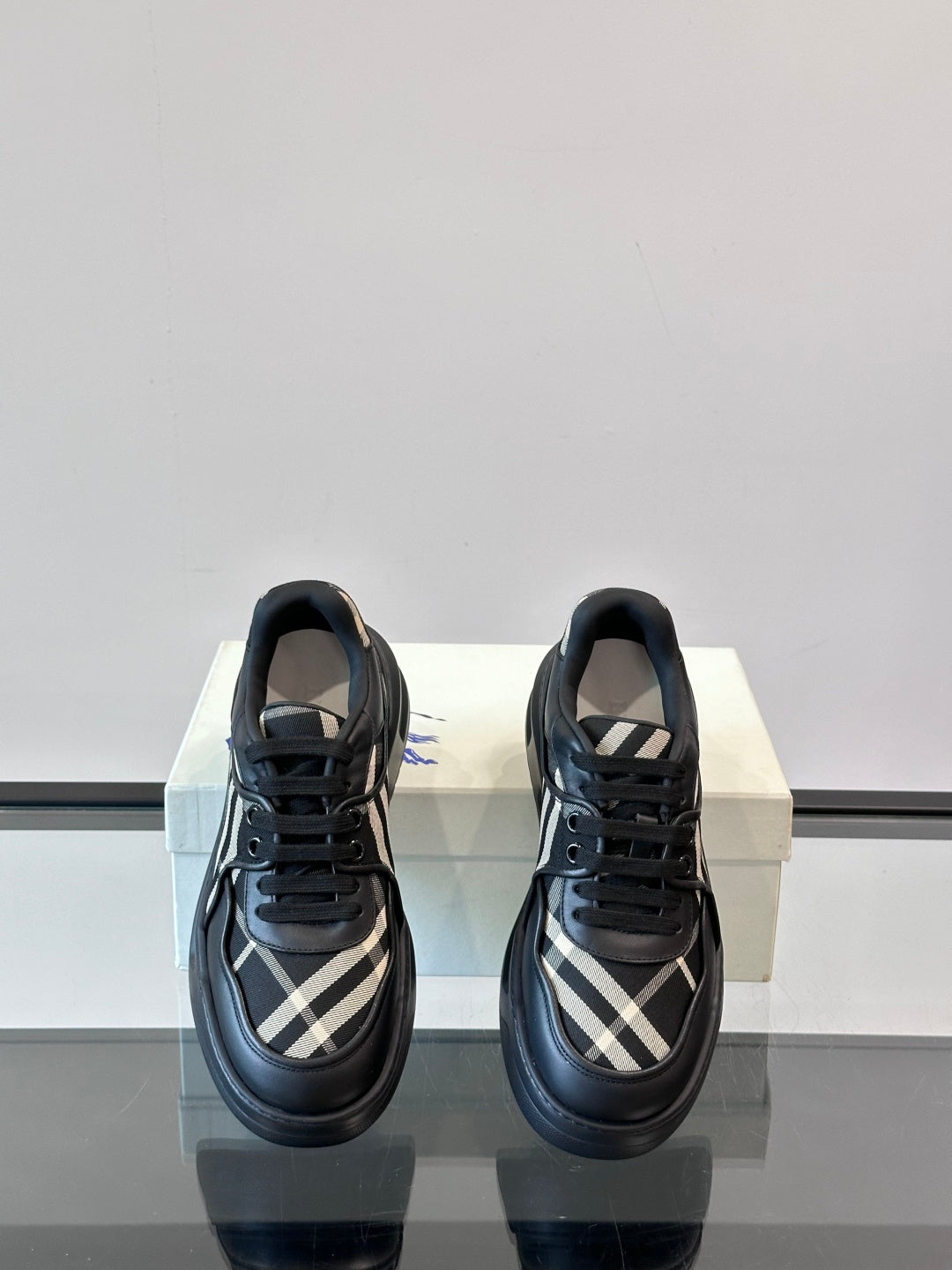 Black lace-up sneakers with plaid quarter panels and low chunky outsole, front view