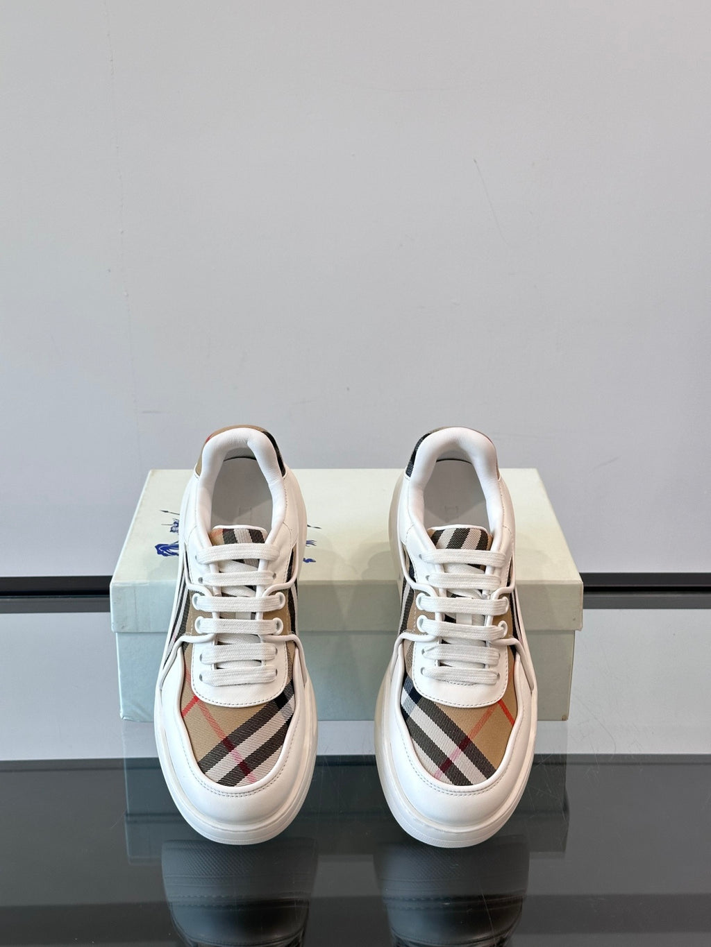 White leather lace-up sneakers, top view showing tongue and Burberry check sides