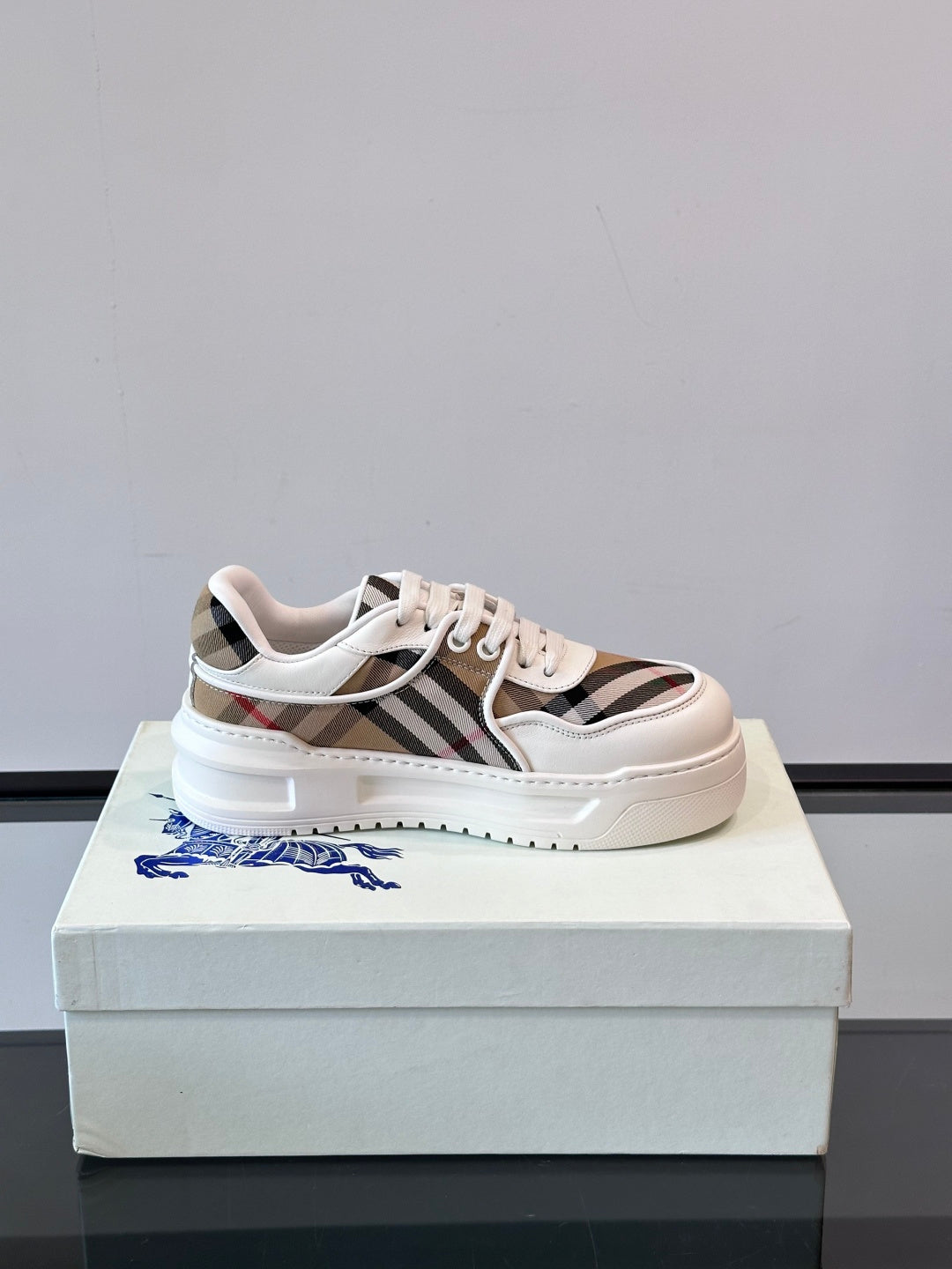 White leather low-top sneakers with Burberry check stripe and lace-up front, side view