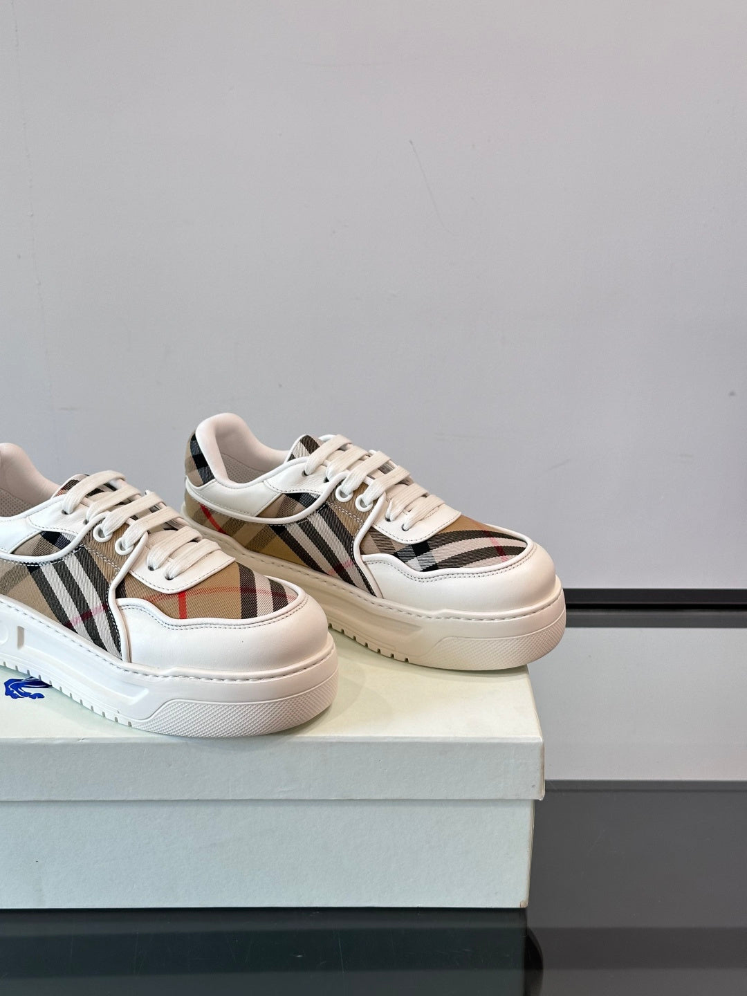 White leather low-top sneakers, angled view with Burberry check stripe and laces