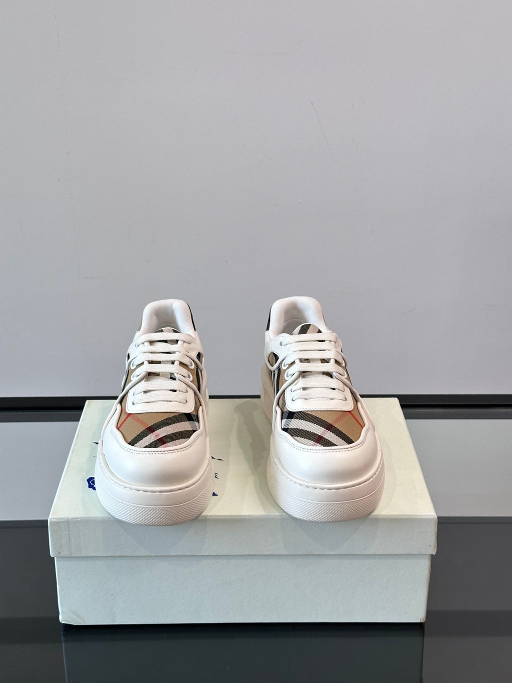 Pair of white leather lace-up sneakers, side view with Burberry check panels