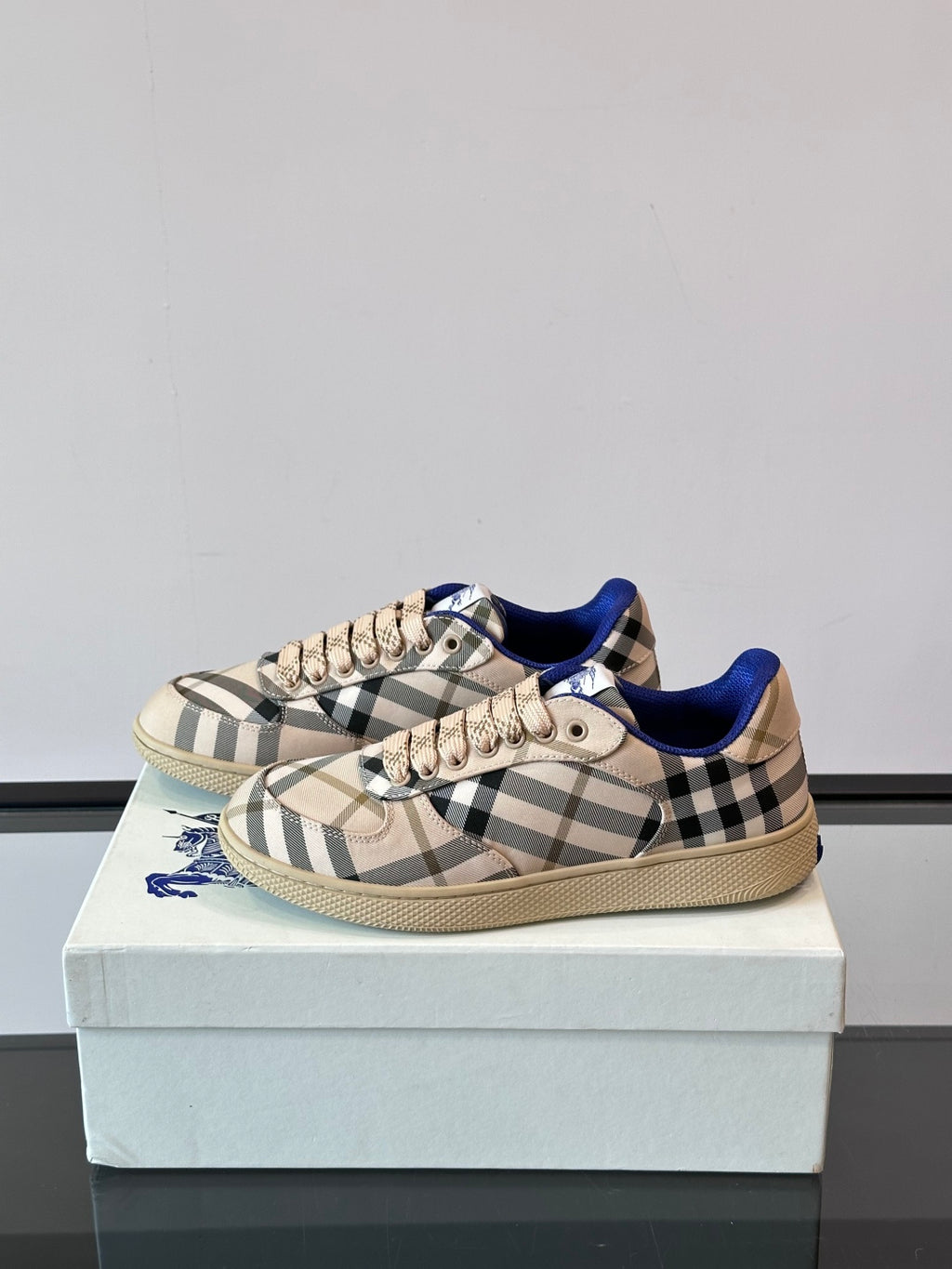 Burberry plaid lace-up sneakers, side view on box; blue trim and tan sole