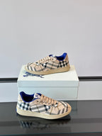 Burberry sneakers on box, angled view; beige plaid fabric, blue collar and tan sole