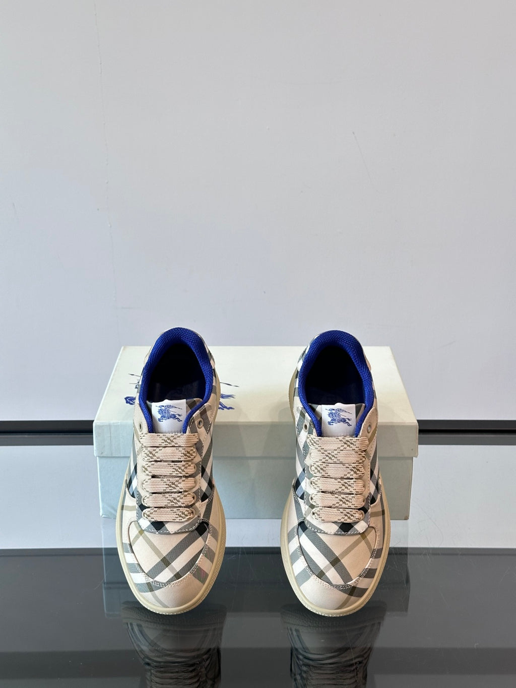 Burberry sneakers, straight-on view; beige plaid uppers with blue laces and collar