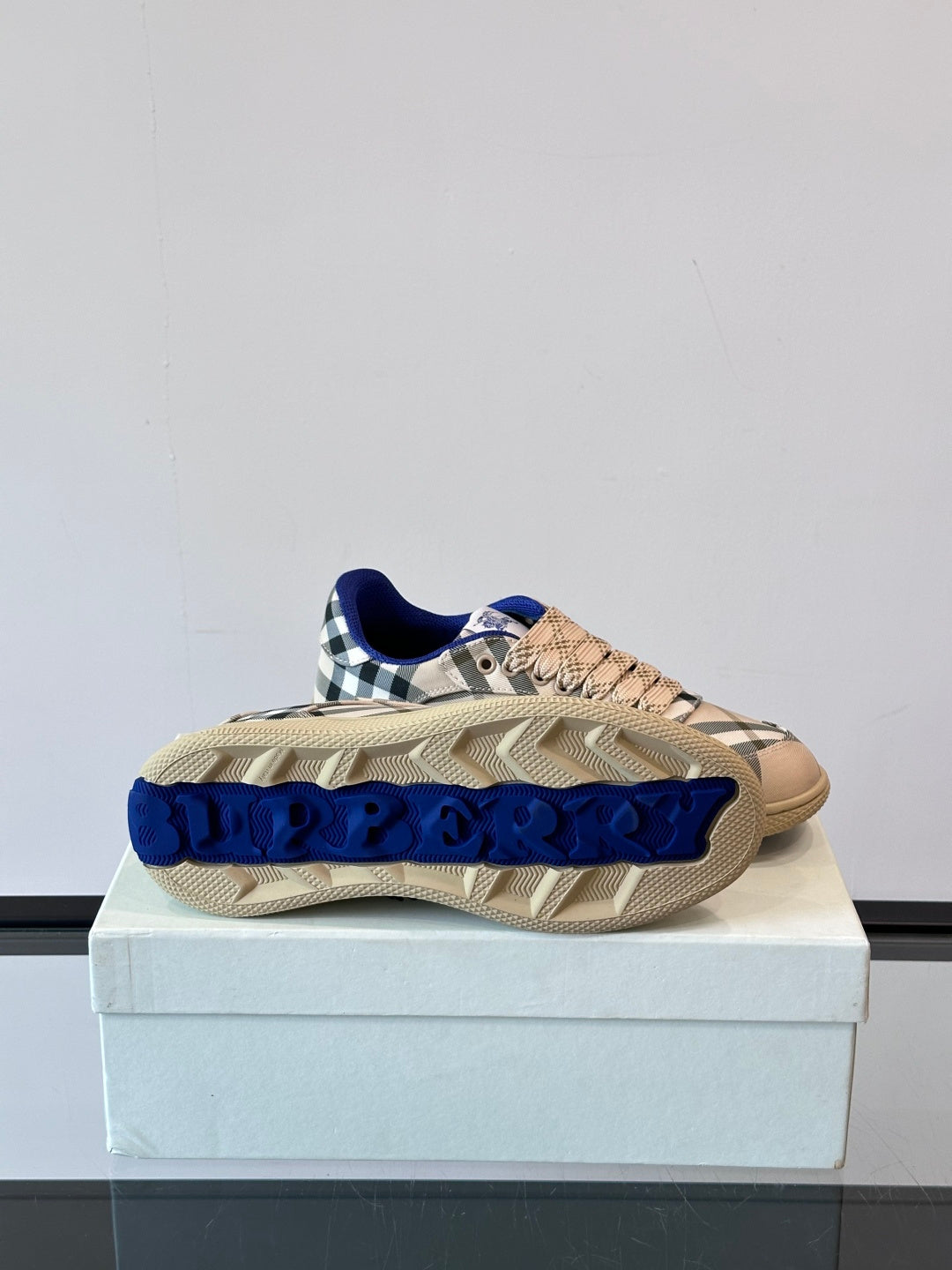 Burberry sneaker outsole view on box; beige tread with blue Burberry lettering