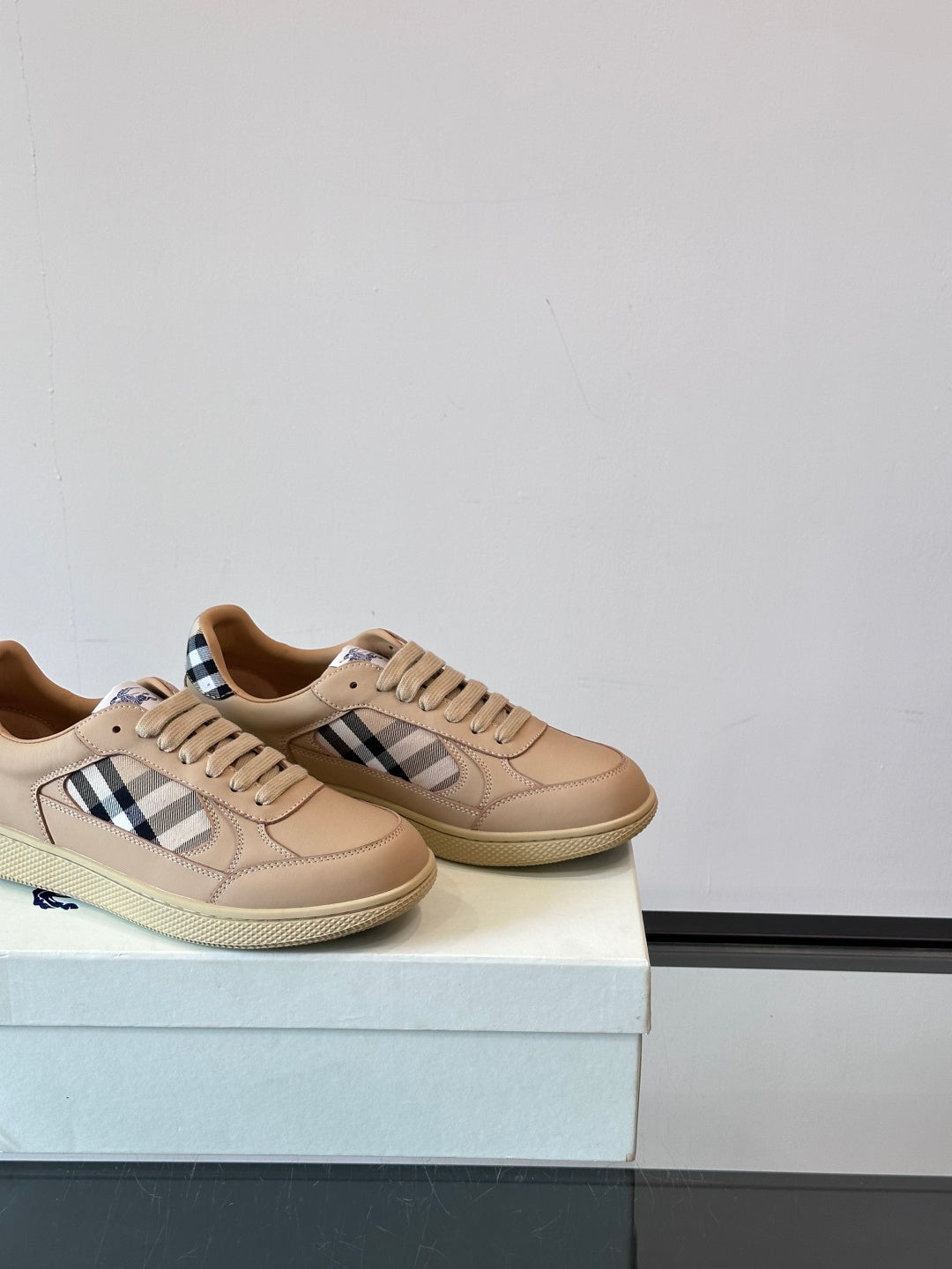 Sneakers on display box: beige leather with Burberry check panels and laces