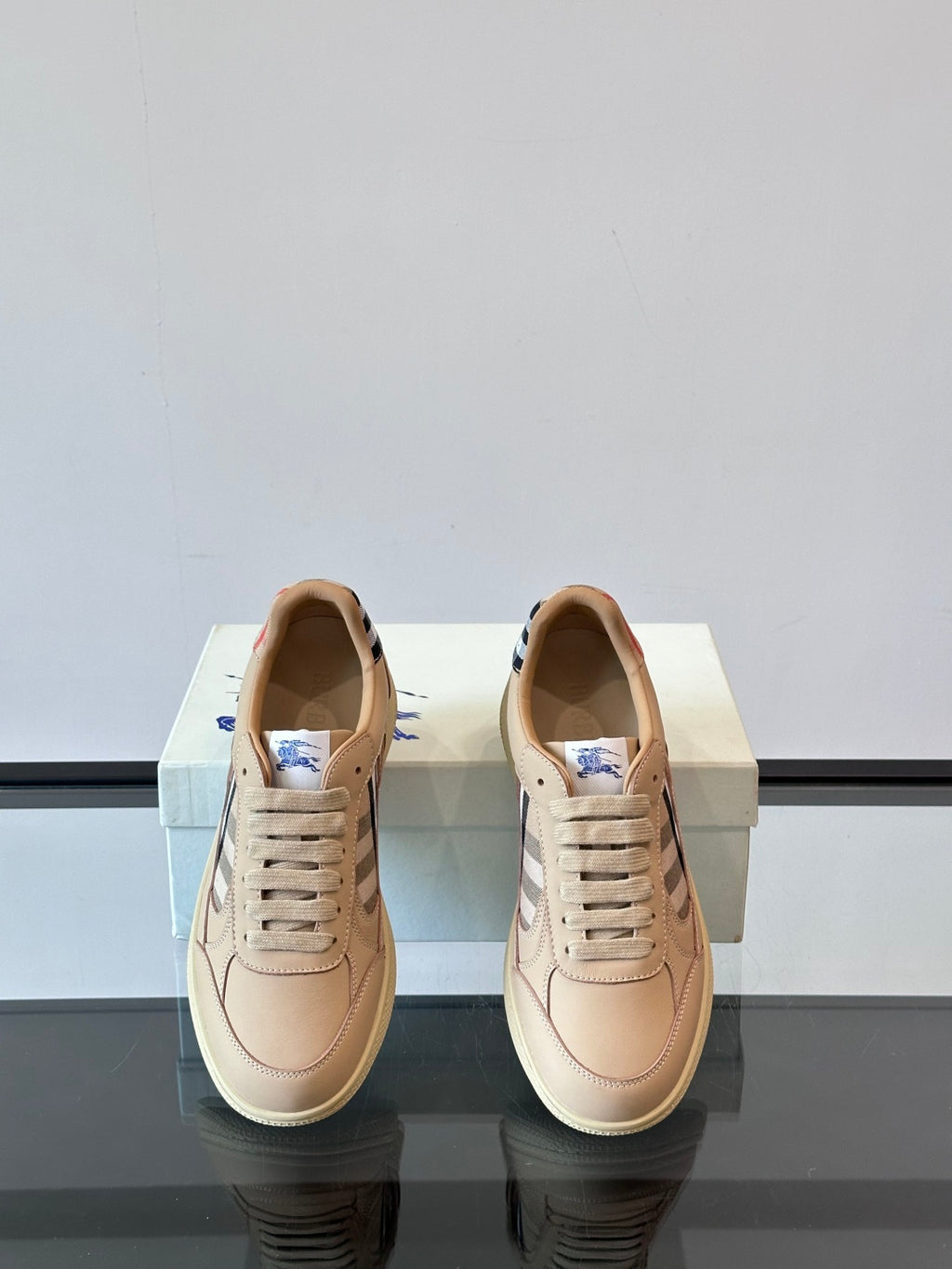 Beige sneakers showing insides and lace-up fronts with Burberry check detail