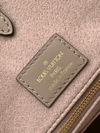 Louis Vuitton leather bag interior tag with gold text on taupe fabric