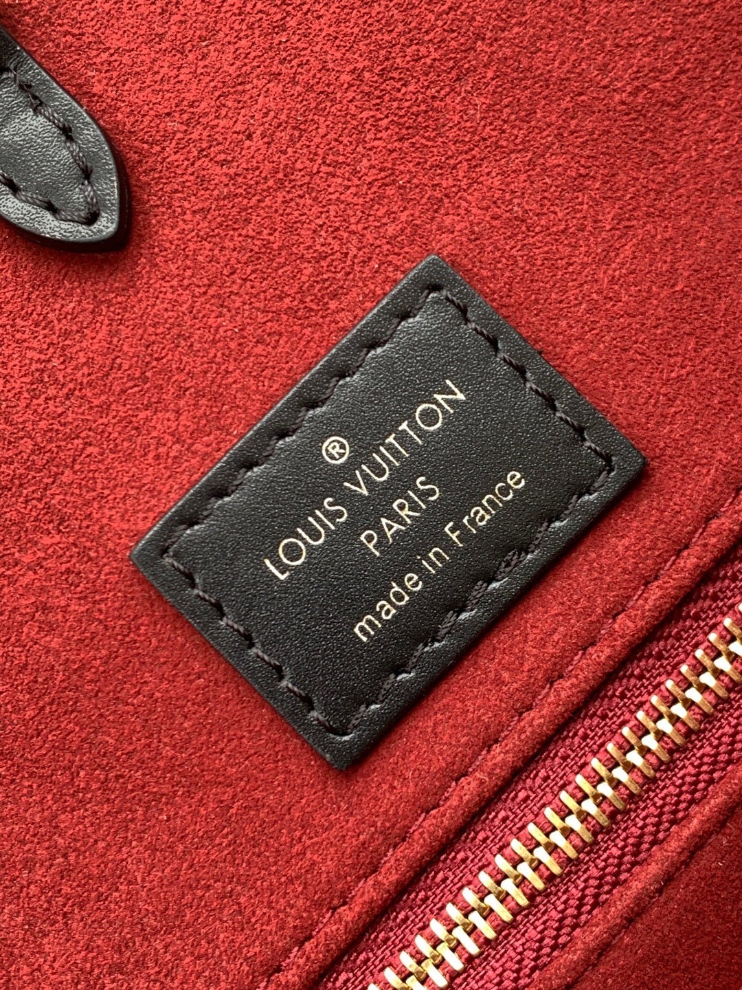 Louis Vuitton tag on red fabric reading “made in France” beside the zipper