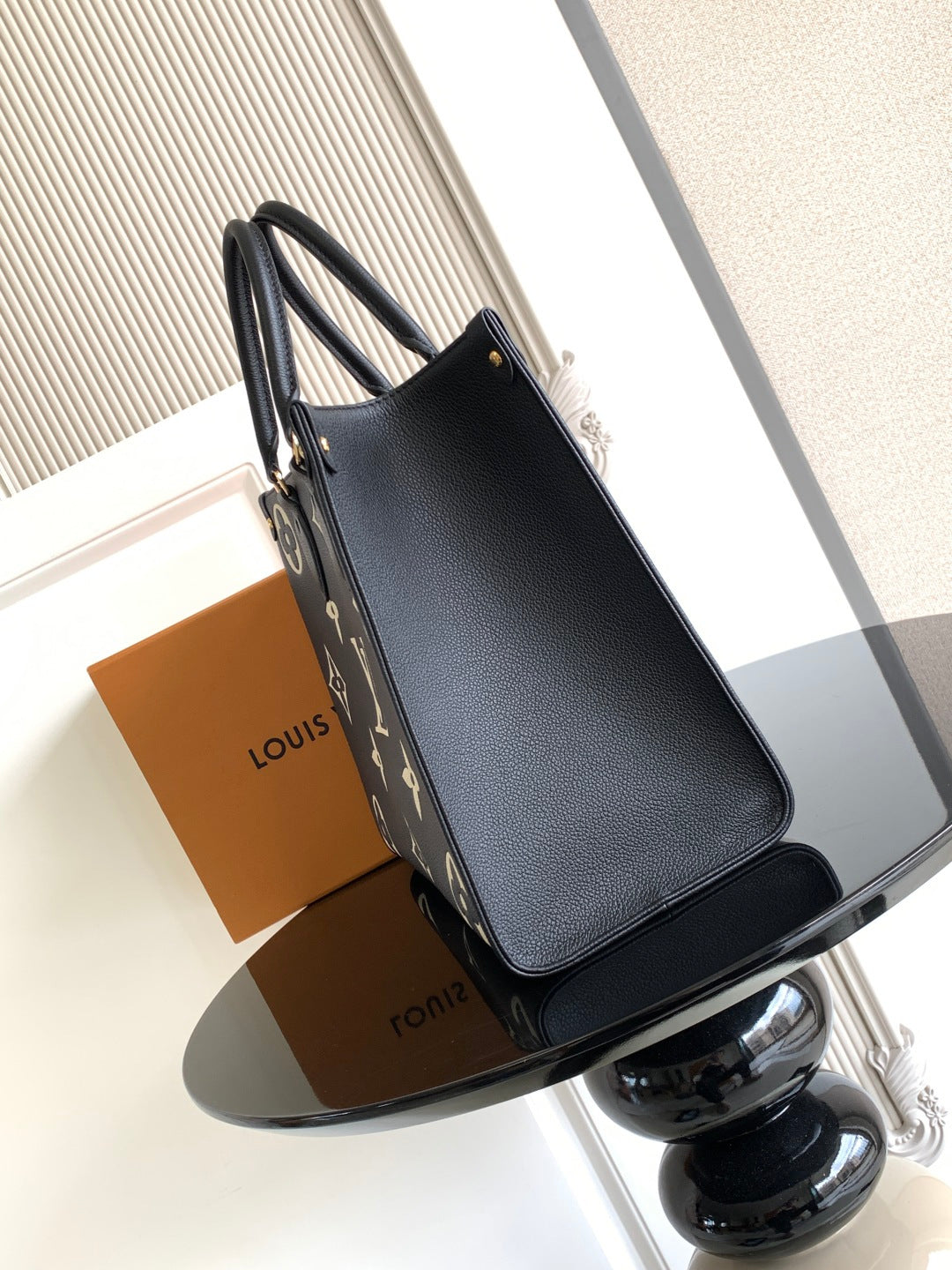 Louis Vuitton bag with black textured finish, long handles, and exterior logo panel