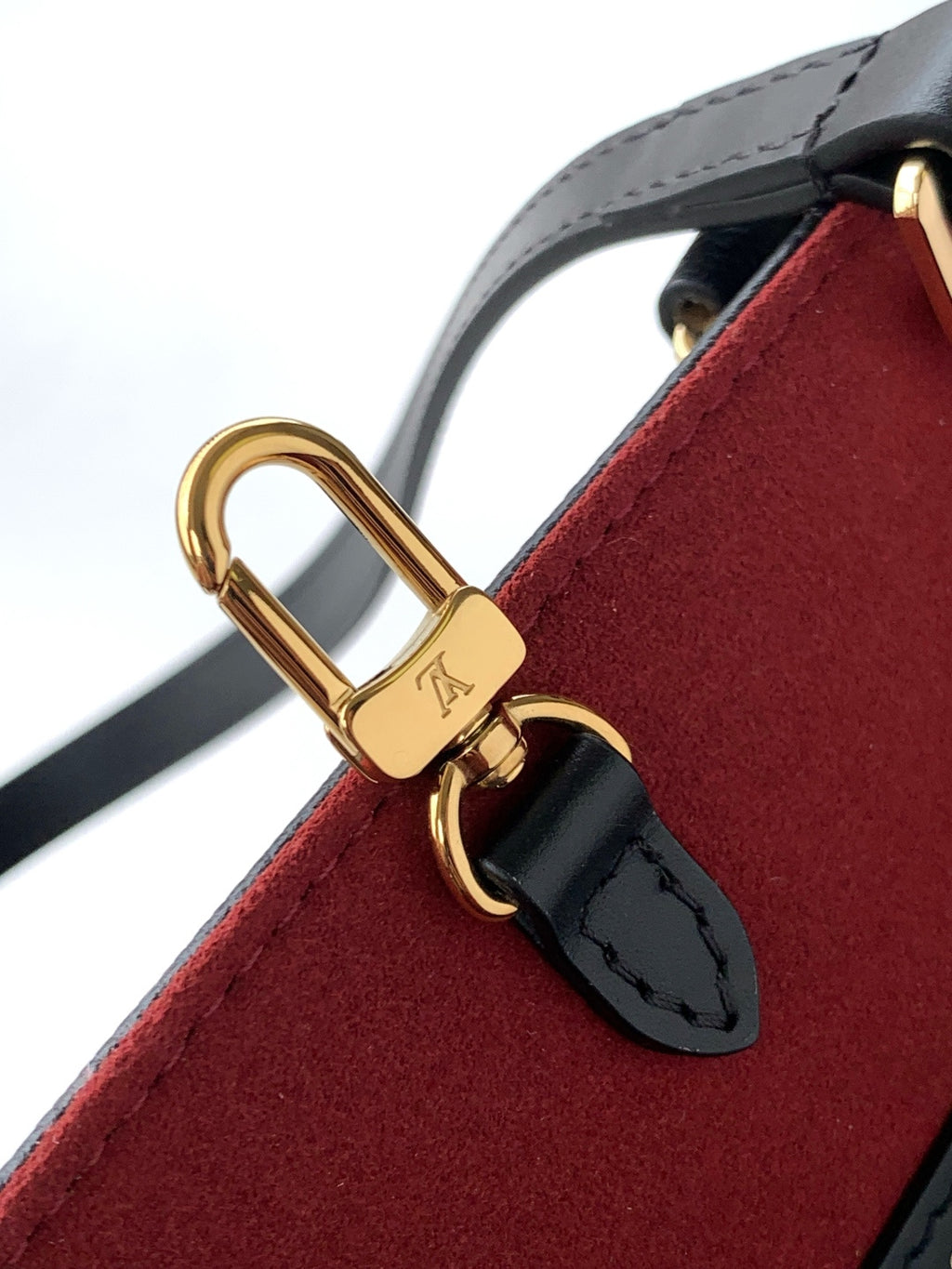 Louis Vuitton strap detail with gold lock clasp on red felt-like lining
