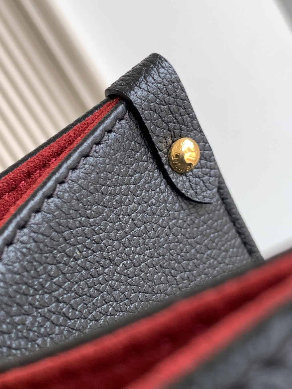 Louis Vuitton bag corner detail with gold snap stud on textured black leather