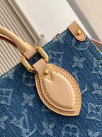 Louis Vuitton denim tote bag close-up of oval leather strap and gold buckle