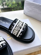 Close-up of black Dior slide sandal with white printed logo strap