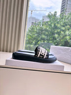 Black Dior slide sandal with white logo band, resting on a box